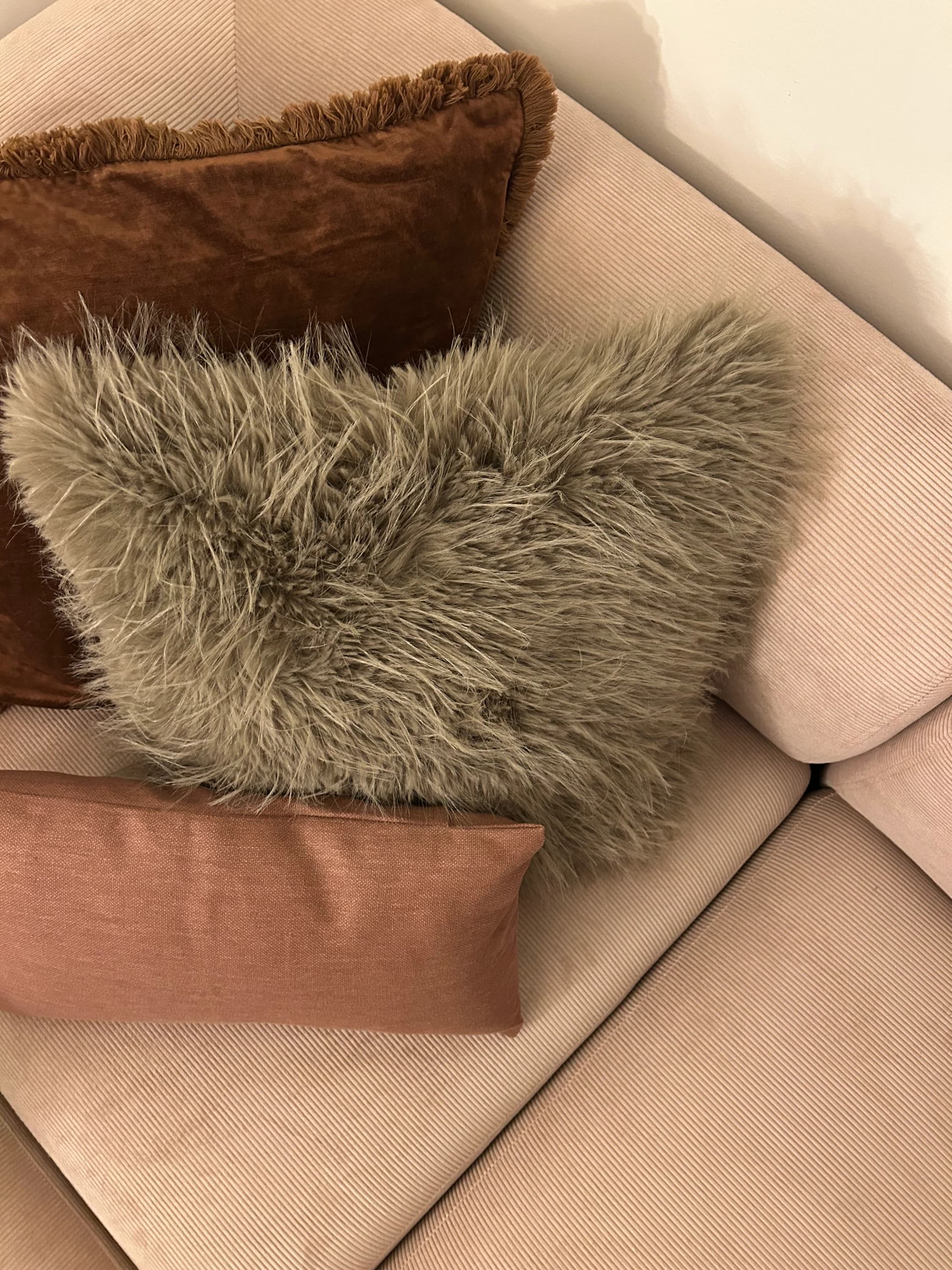 Coussins en velours, fausse fourrure et lin dans des tons terre, sur un canapé en velours côtelé