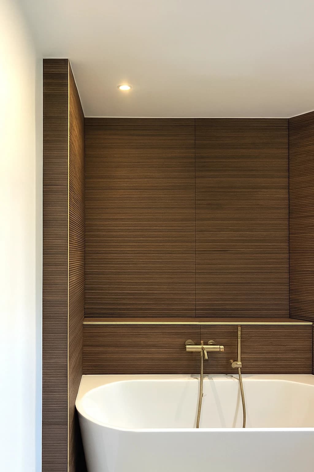 Salle de bain habillée de bois foncé, baignoire îlot et robinetterie dorée, appartement à Paris 16ᵉ