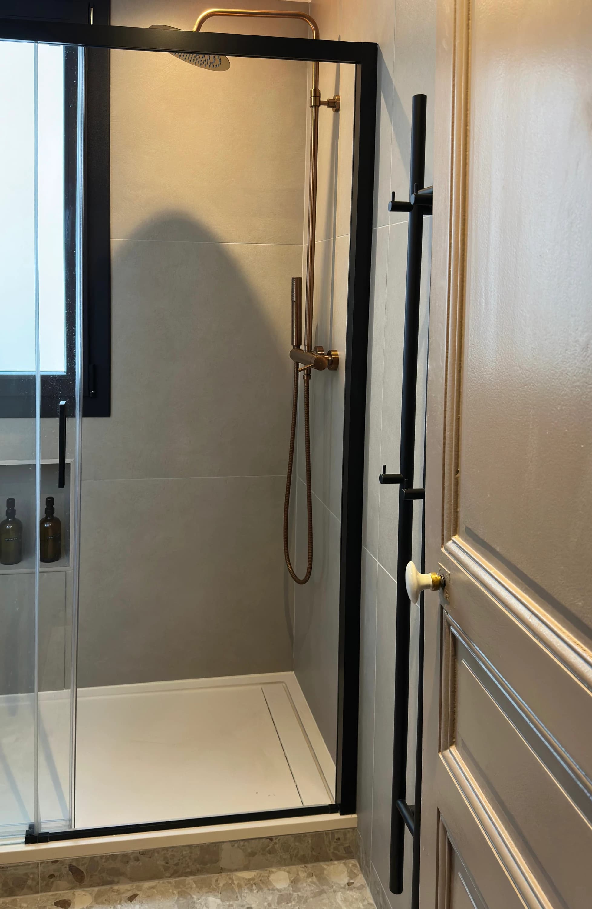 Douche à parois vitrées et cadre noir, robinetterie dorée, salle de bains rénovée rue Ordener, Paris 18ᵉ
