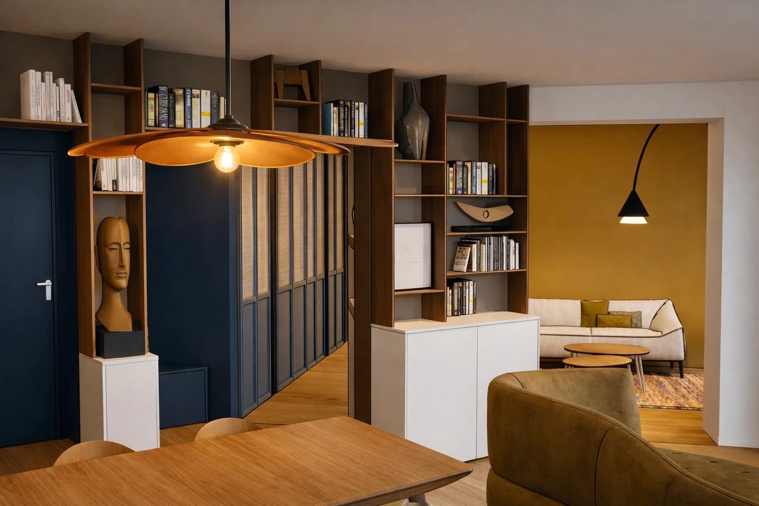 Vue 3D d'une entrée bordée d'une bibliothèque sur mesure en bois et de placards bleu nuit, appartement à Vincennes